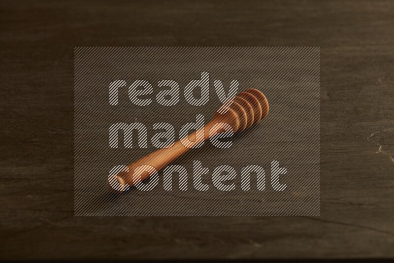 Wooden honey dipper on black slate background