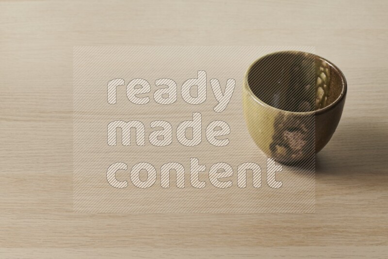 A multicolored pottery cup on light wooden background
