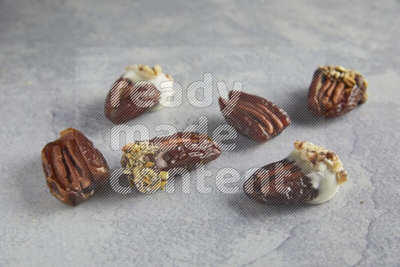 group of pecan stuffed dates plain and covered with dark and white chocolate  on alight grey background