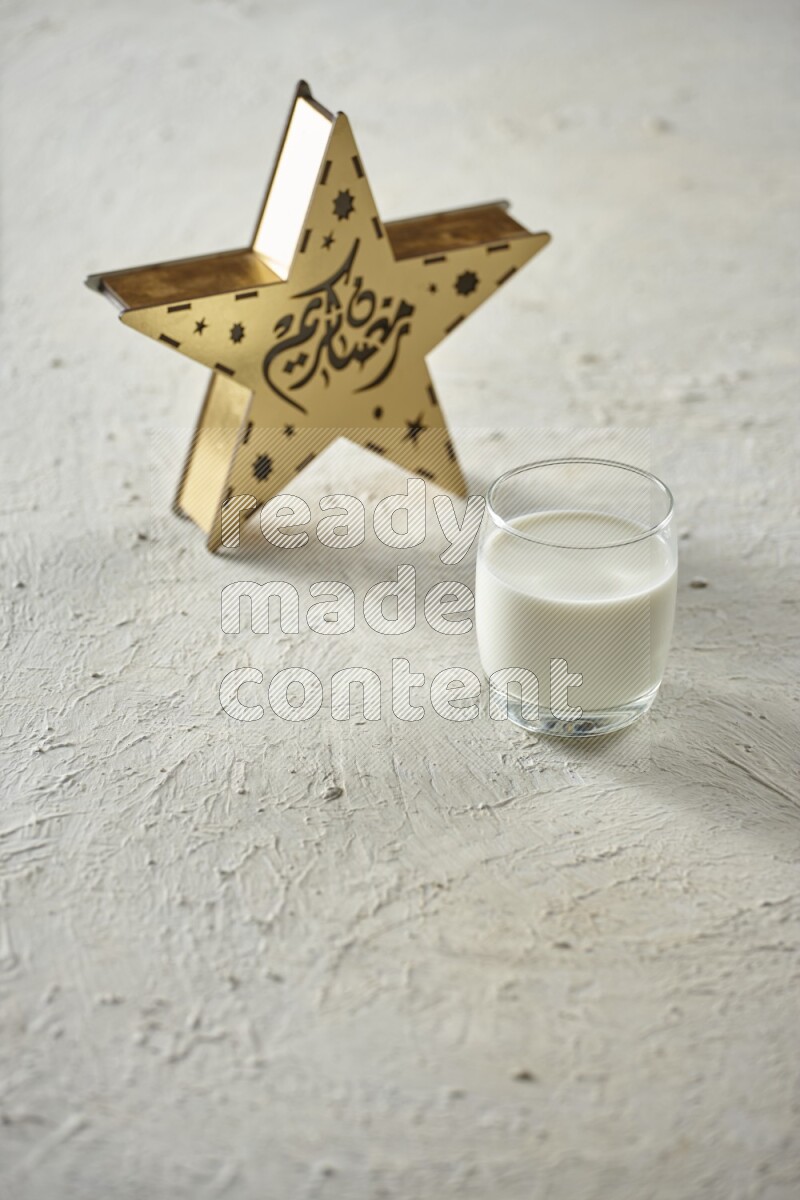 A wooden golden star lantern with different drinks, dates, nuts, prayer beads and quran on textured white background
