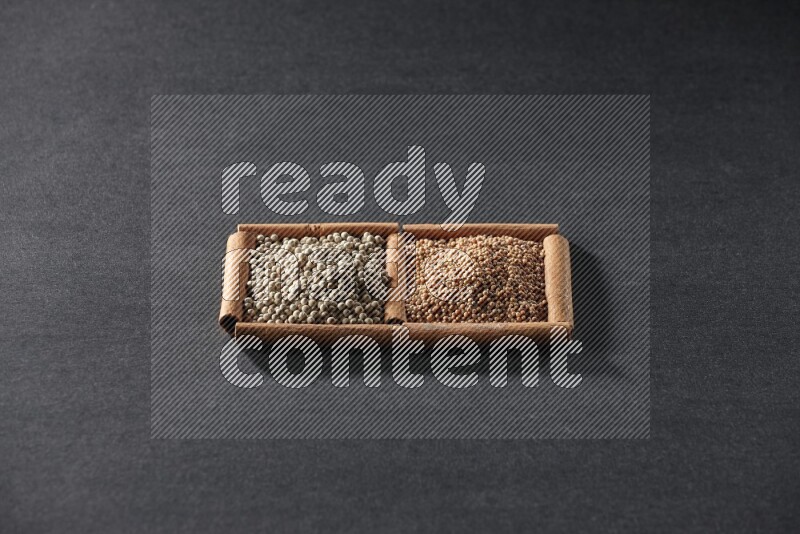 مربعان من أعواد القرفة ممتلئان بحبوب الخردل وحبوب الفلفل الأبيض علي خلفية سوداء