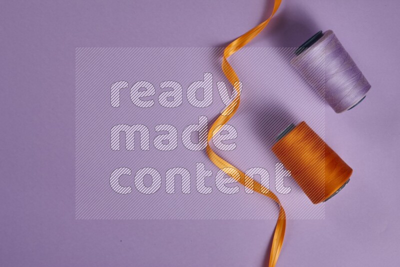 مجموعة من أدوات الخياطة والتفصيل برتقالية اللون على خلفية أرجوانية