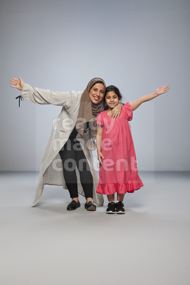A girl and her mother interacting with the camera on gray background