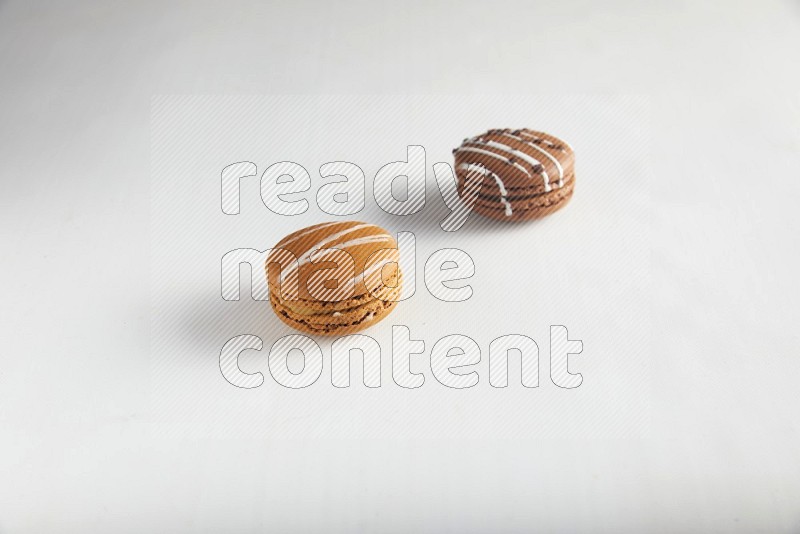 45º Shot of of two assorted Brown Irish Cream, and Brown white Chocolate Caramel macarons on white background