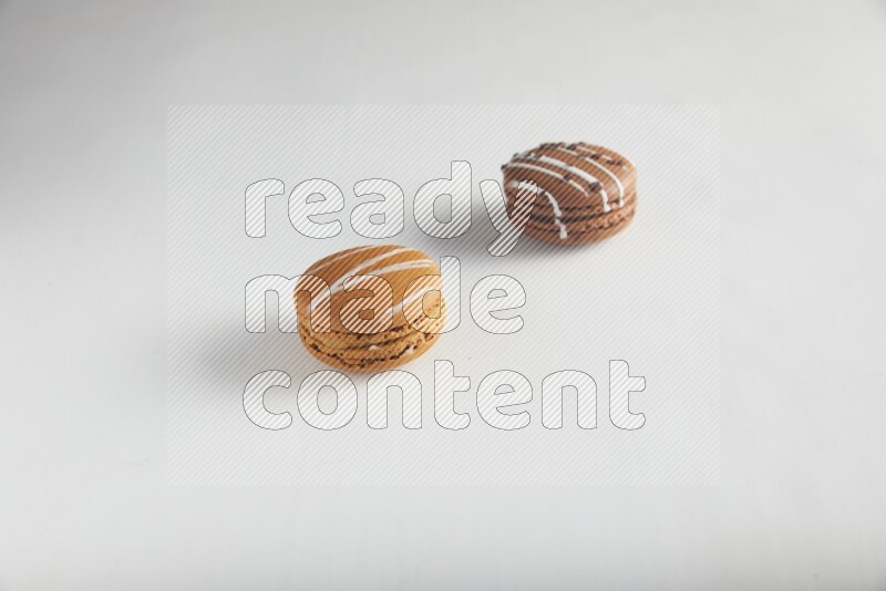 45º Shot of of two assorted Brown Irish Cream, and Brown white Chocolate Caramel macarons on white background