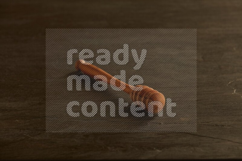 Wooden honey dipper on black slate background