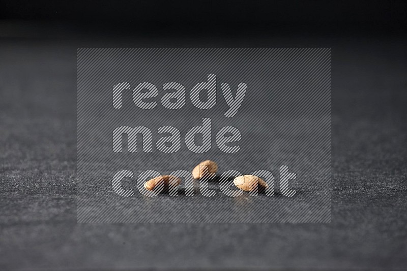 3 peeled almonds on a black background in different angles