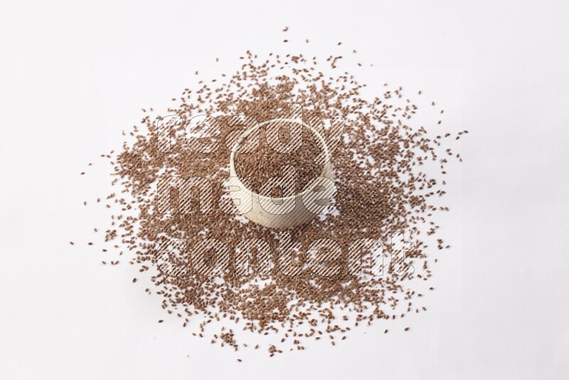 وعاء بيج فخاري ممتلئ بحبوب بذر الكتان مع بعض الحبوب المتناثرة علي خلفية بيضاء