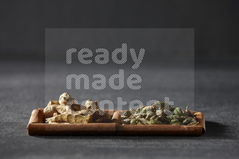 2 squares of cinnamon sticks full of cardamom and turmeric fingers on black flooring