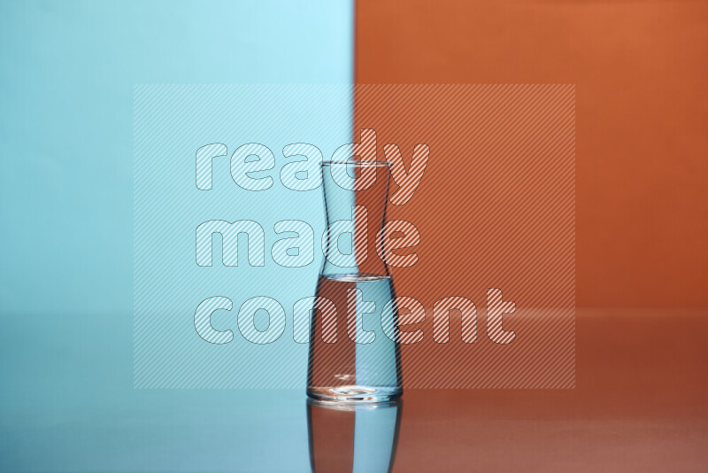 The image features a clear glassware filled with water, set against light blue and dark orange background