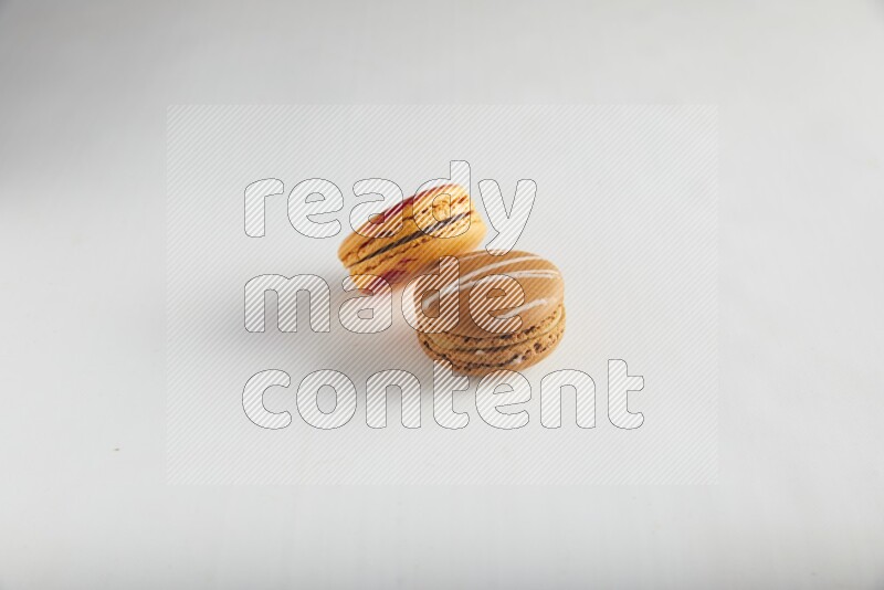 45º Shot of of two assorted Brown Irish Cream, and Orange Exotic macarons on white background