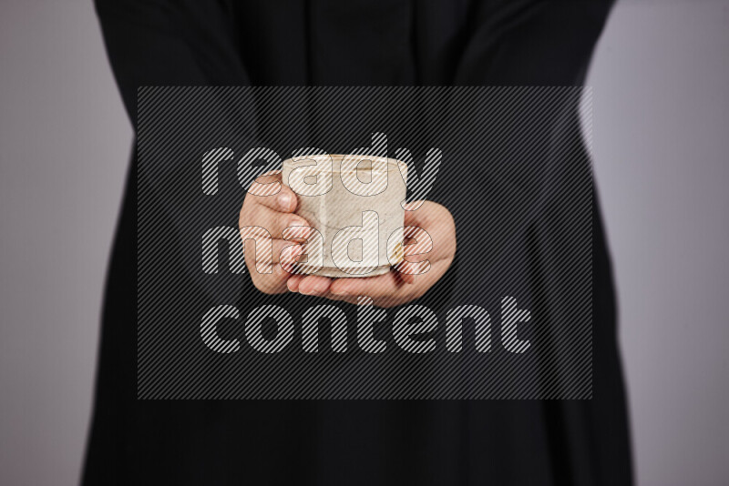 A woman in black abaya holding different pottery essentials in different positions