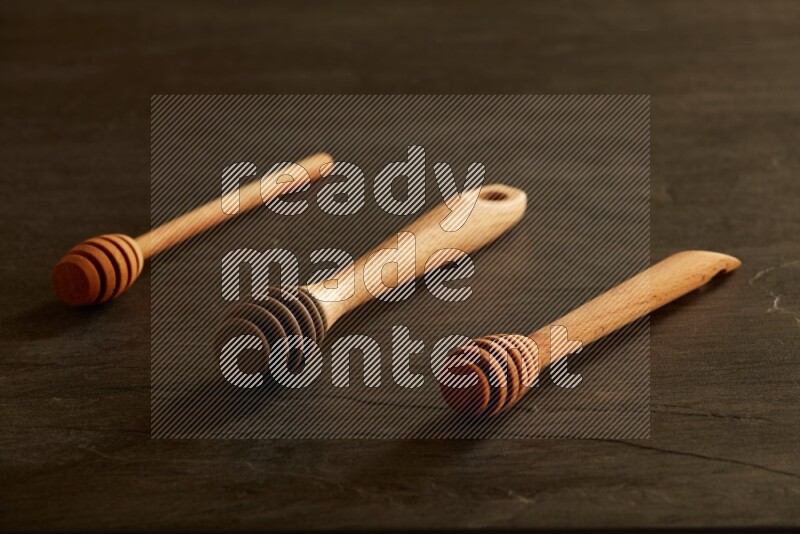 Wooden honey dipper on black slate background