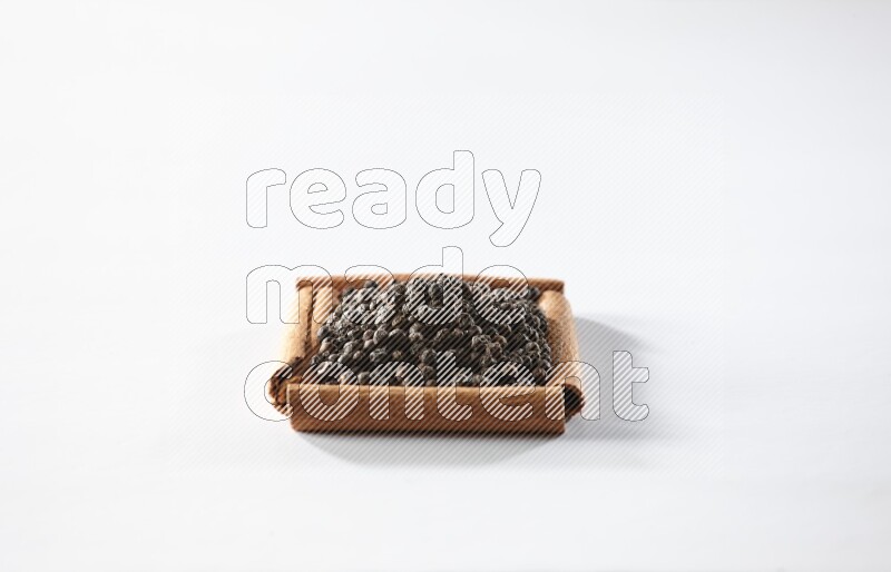 A single square of cinnamon sticks full of black pepper on white flooring
