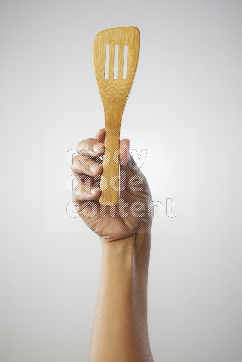 Male Hand Holding Slotted Turner on white background