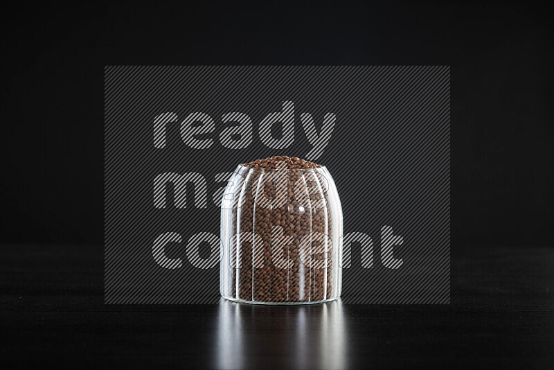 Brown lentils in a glass jar on black background