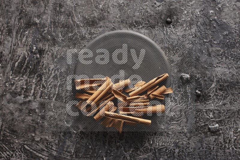 أعواد من القرفة علي طبق أسود علي خلفية سوداء