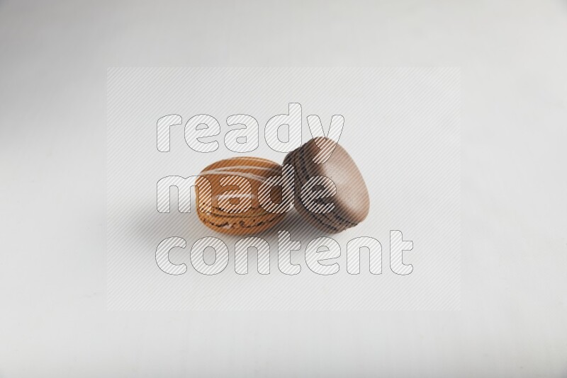 45º Shot of of two assorted Brown Irish Cream, and Brown Dark Chocolate macarons on white background
