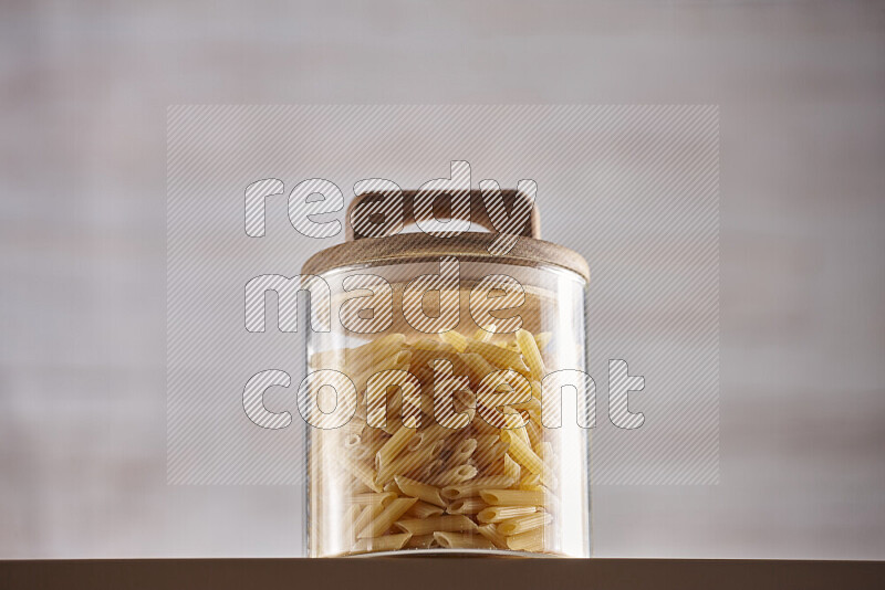 Raw pasta in glass jars on beige background