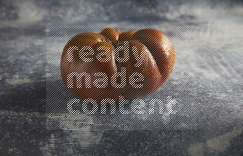 45 degree single heirloom tomato on a textured rustic blue background