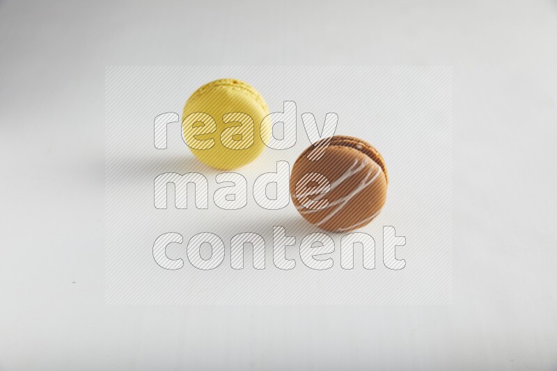 45º Shot of of two assorted Brown Irish Cream, and Yellow Lemon macarons on white background