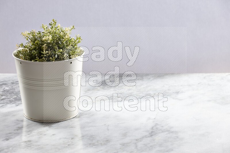 Artificial plant in white pot on grey marble background
