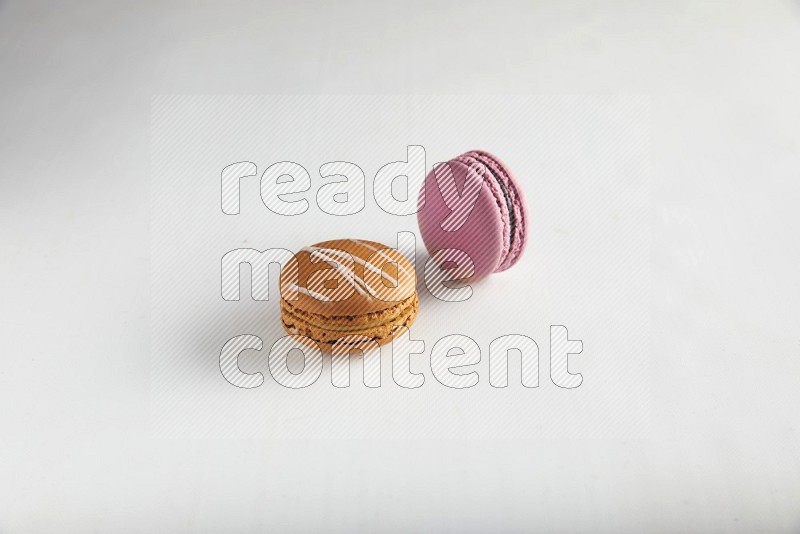 45º Shot of of two assorted Brown Irish Cream, and Purple Strawberry macarons on white background