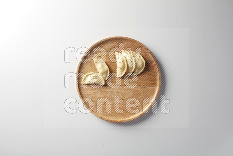 Five Sambosas on a wooden round plate on a white background