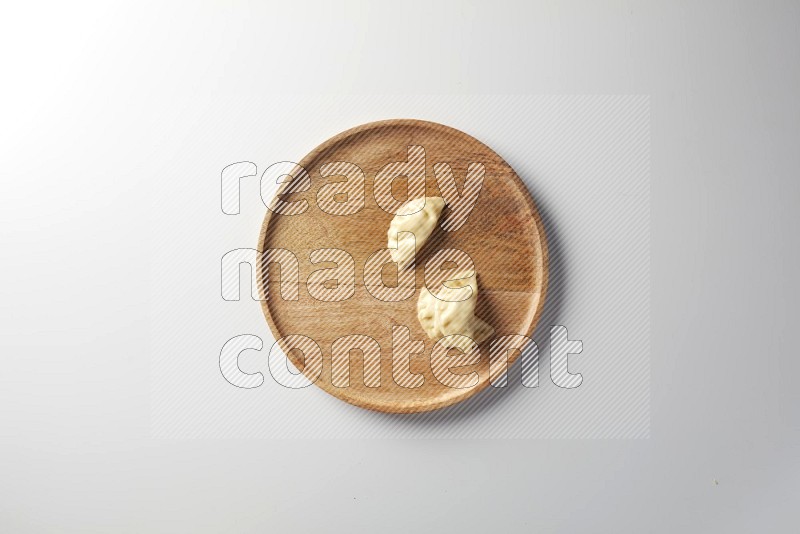 Three Sambosas on a wooden round plate on a white background