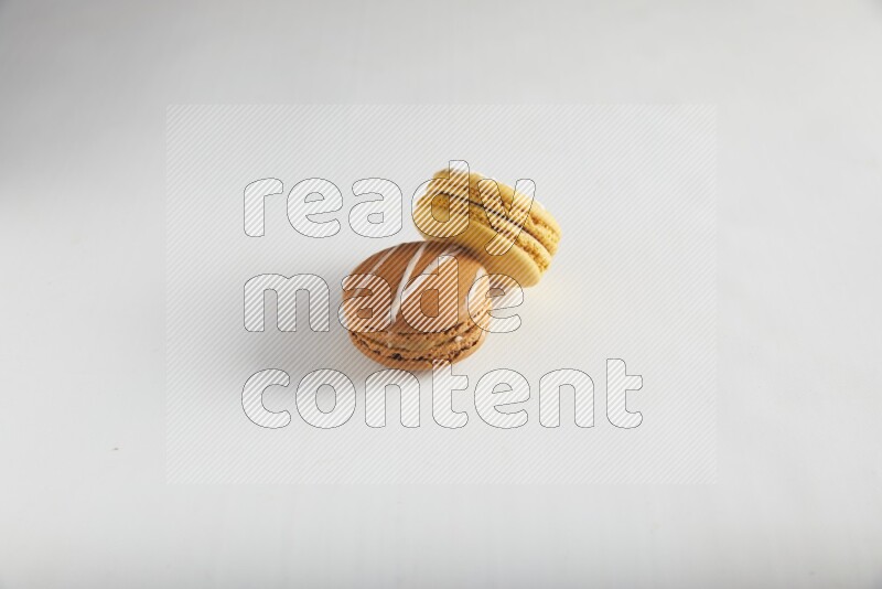 45º Shot of of two assorted Brown Irish Cream, and Yellow Piña Colada macarons on white background