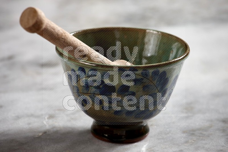 Decorative Pottery Bowl with wooden honey handle in it, on grey marble flooring, 15 degree angle