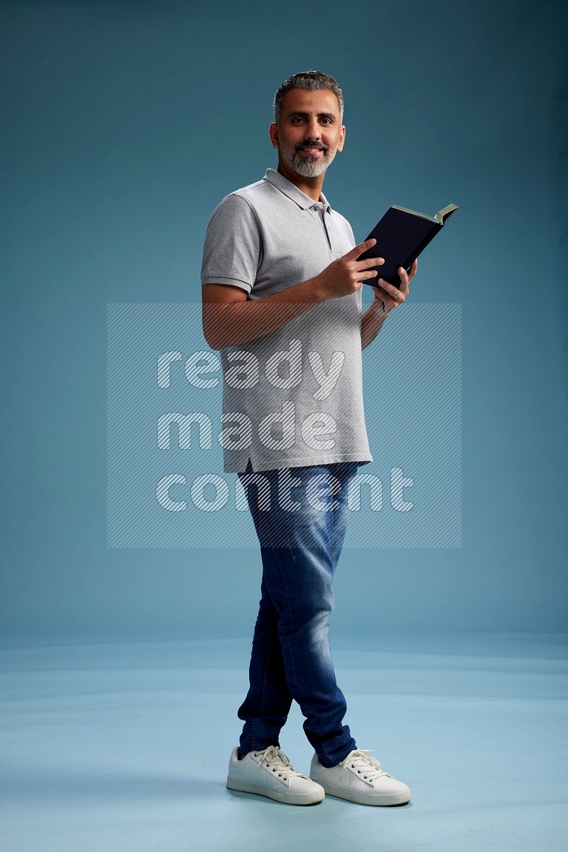 Man Standing reading book on blue background