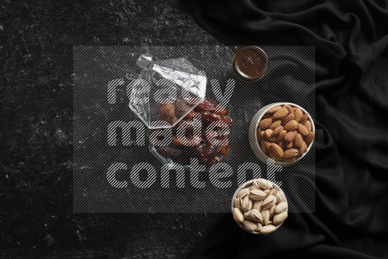 Dates in glass bowl with coffee and nuts in a dark setup