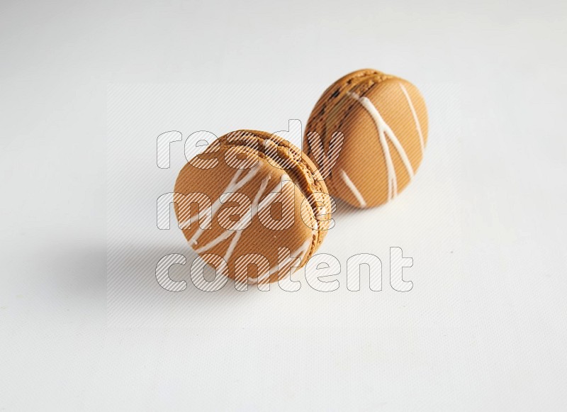 45º Shot of two Brown Irish Cream macarons on white background