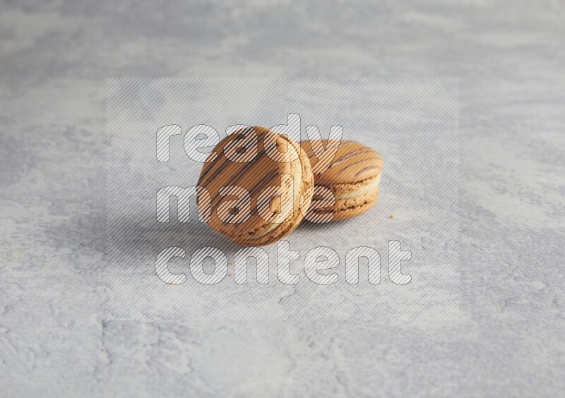 45º Shot of two light brown  Almond Cream macarons  on white  marble background