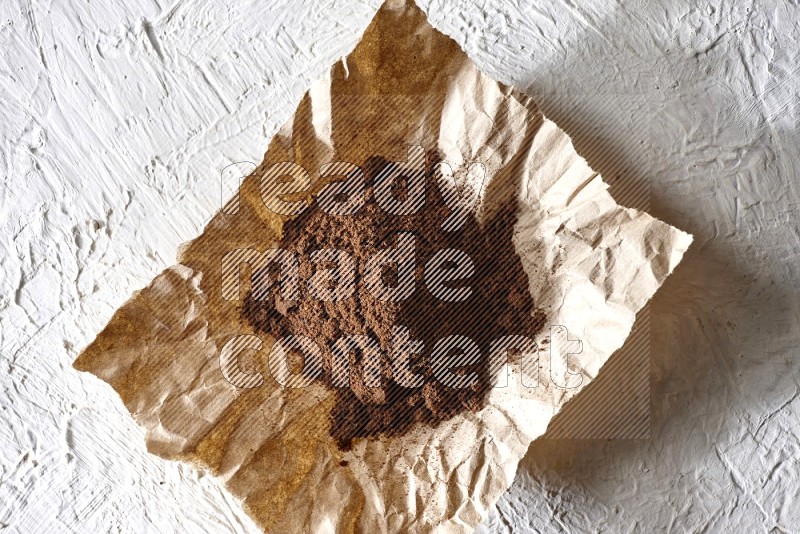 Cloves powder on crumpled piece of paper on a textured white flooring