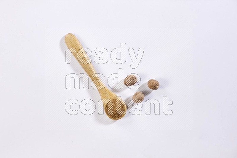 A wooden spoon full of nutmeg powder with nutmeg seeds beside it on a white flooring in different angles