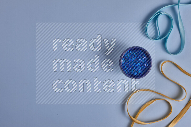 مجموعة من أدوات الخياطة والتفصيل صفراء وزرقاء اللون على خلفية زرقاء