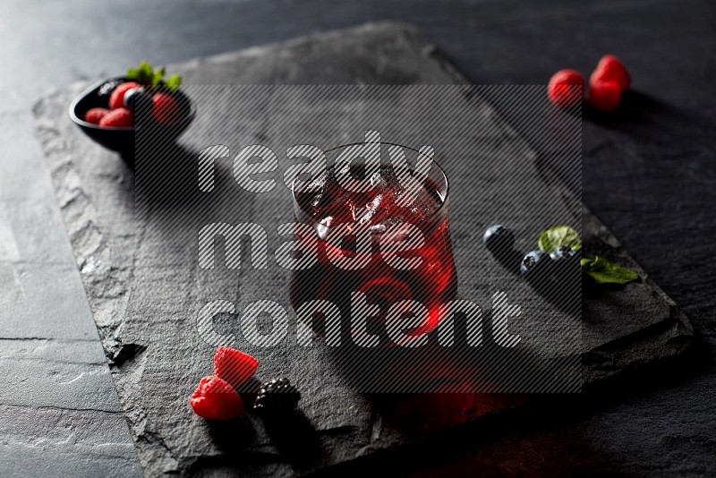 A glass of mixed berries juice on black background