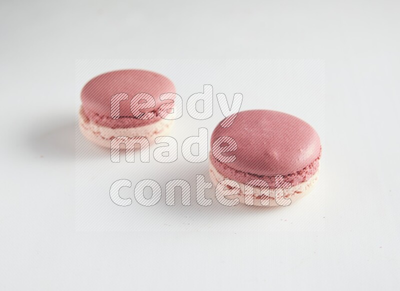 45º Shot of two Pink Litchi Raspberry macarons on white background