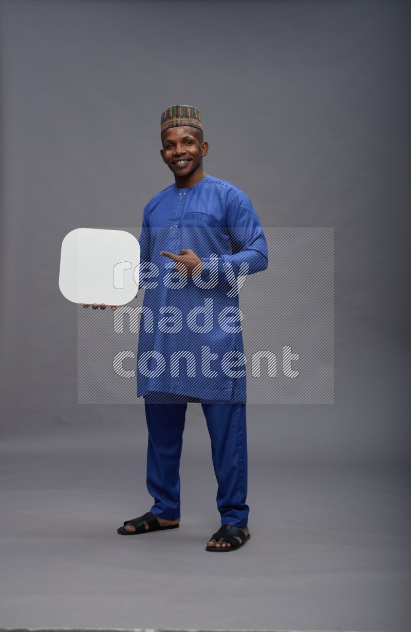 Man wearing Nigerian outfit standing holding social media sign on gray background