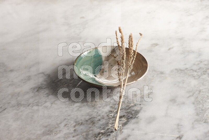 Wheat stalks on multicolored pottery plate on grey marble background
