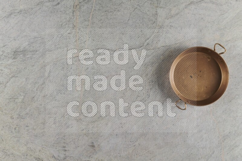 A small copper pan on grey marble background