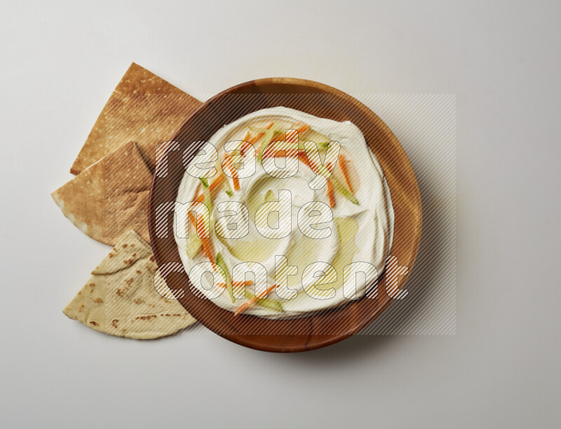 Lebnah garnished with sliced carrots & cucumber in a wooden plate on a white background