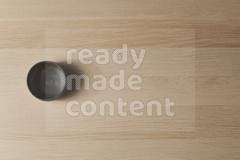 وعاء فخاري أسود على خلفية خشبية فاتحة