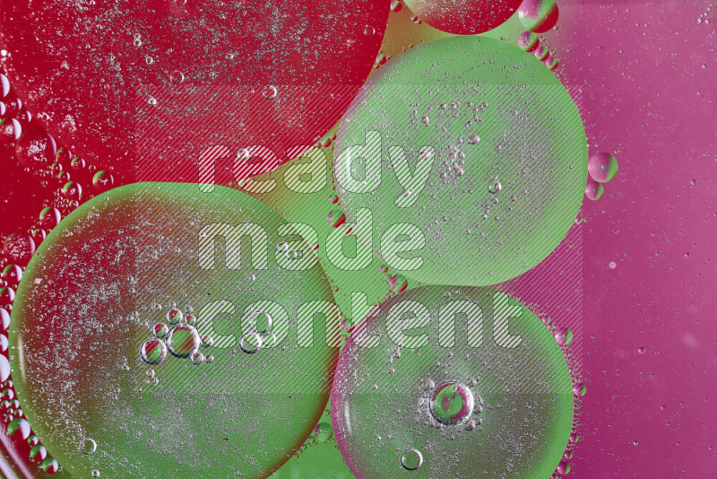 Close-ups of abstract oil bubbles on water surface in shades of pink, green and red
