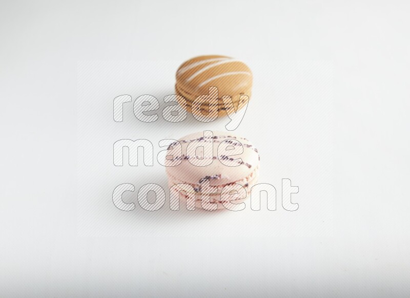 45º Shot of of two assorted Brown Irish Cream, and pink orange blossom macarons on white background