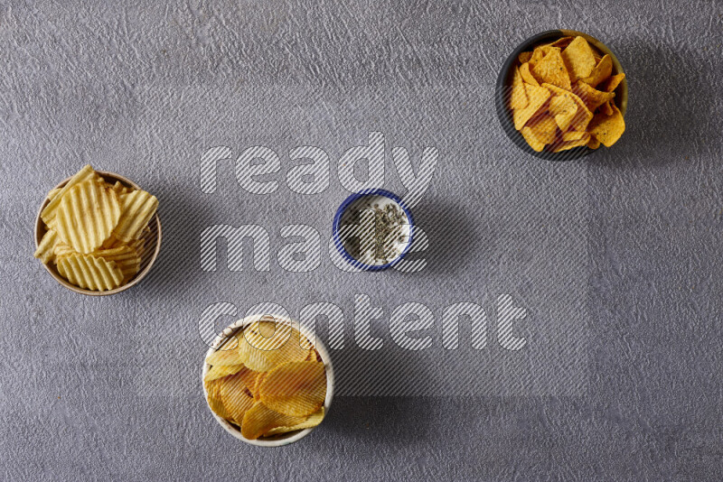 Assorted snacks in pottery bowls on grey background
