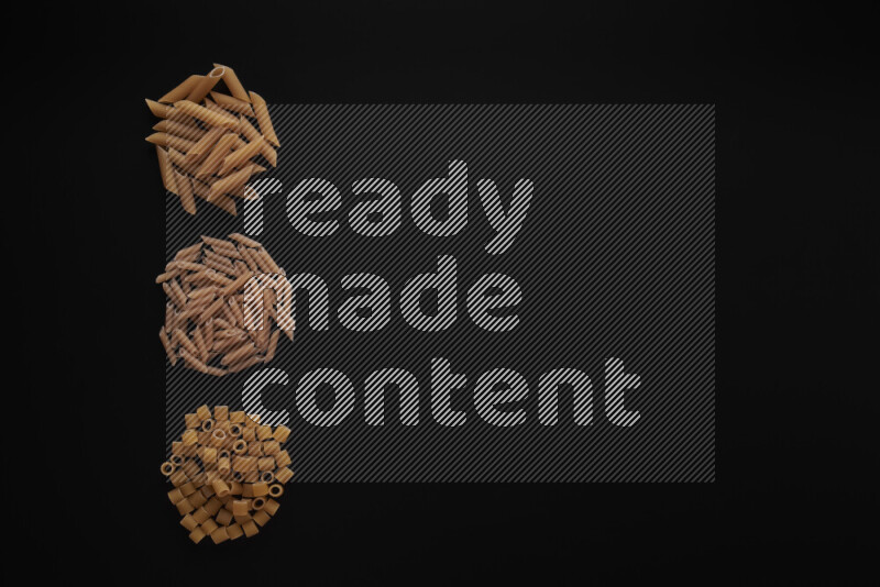 Different pasta types in 3 bunches on black background