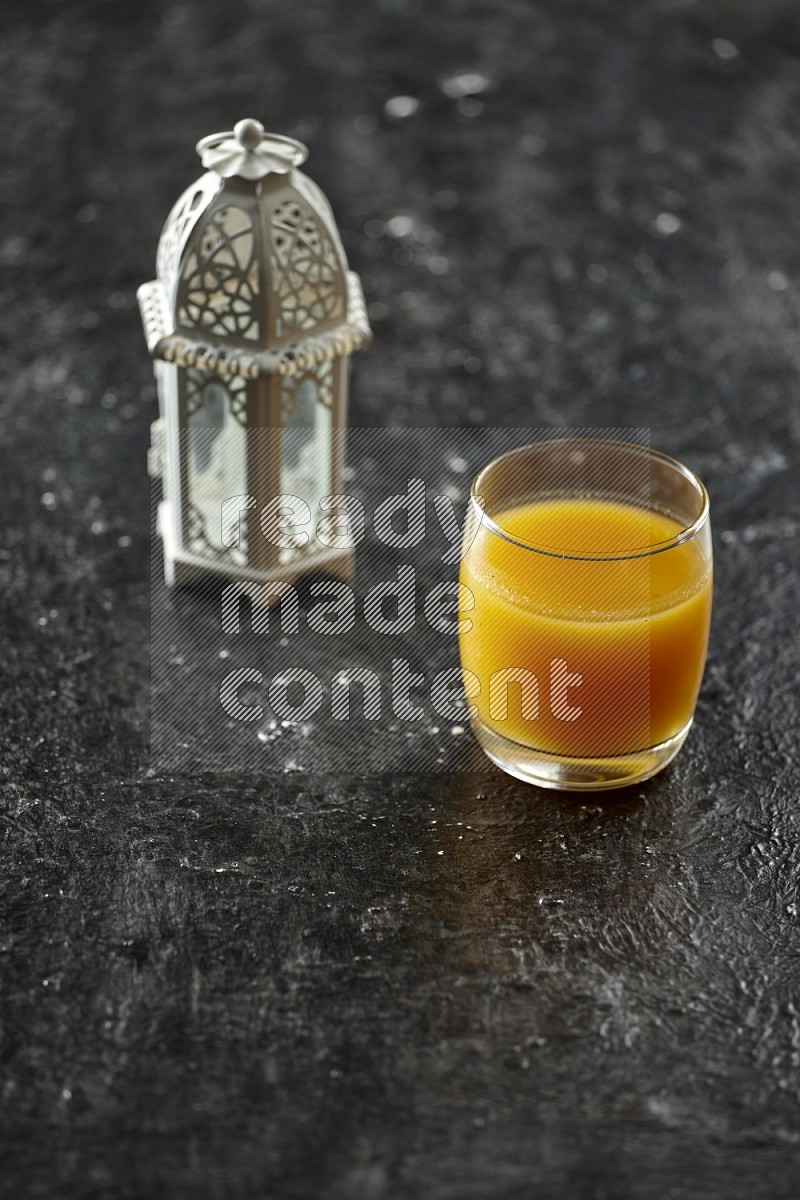 A white lantern with different drinks, dates, nuts, prayer beads and quran on textured black background